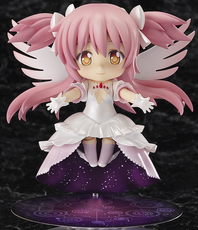 a nendoroid of ultimate madoka. she wears a shiny white dress, with her hair longer and tied up partially in shiny white ribbons. her eyes have a golden glow, and she holds her arms out gently.