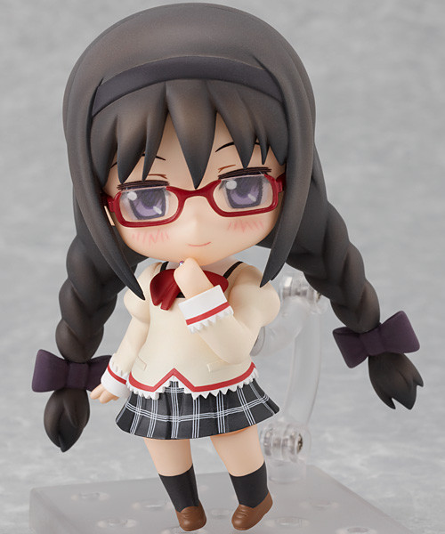a nendoroid of homura akemi, in her school uniform. she has her hair tied in twin braids and is donning her glasses, along with a gentle smile. her school uniform is identical to that of sayaka miki, as described in an earlier passage.