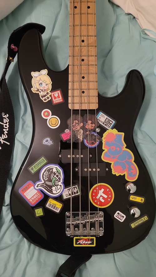 davison full size electric bass in black. the body is covered in various stickers