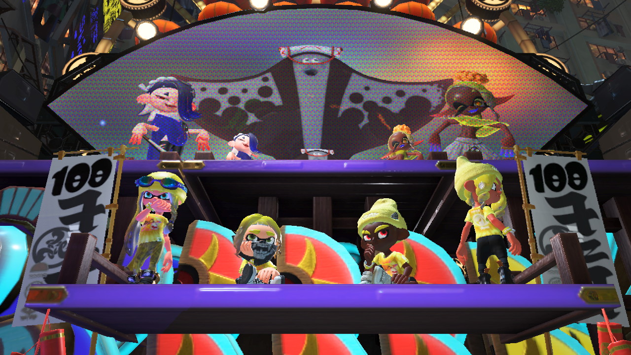 a screenshot from splatoon. two inklings and octolings with yellow ink stand on a platform in front of a stage. the members of deep cut stand on the stage, posing.